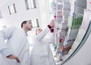 Pharmacy technicians looking at boxes of medication