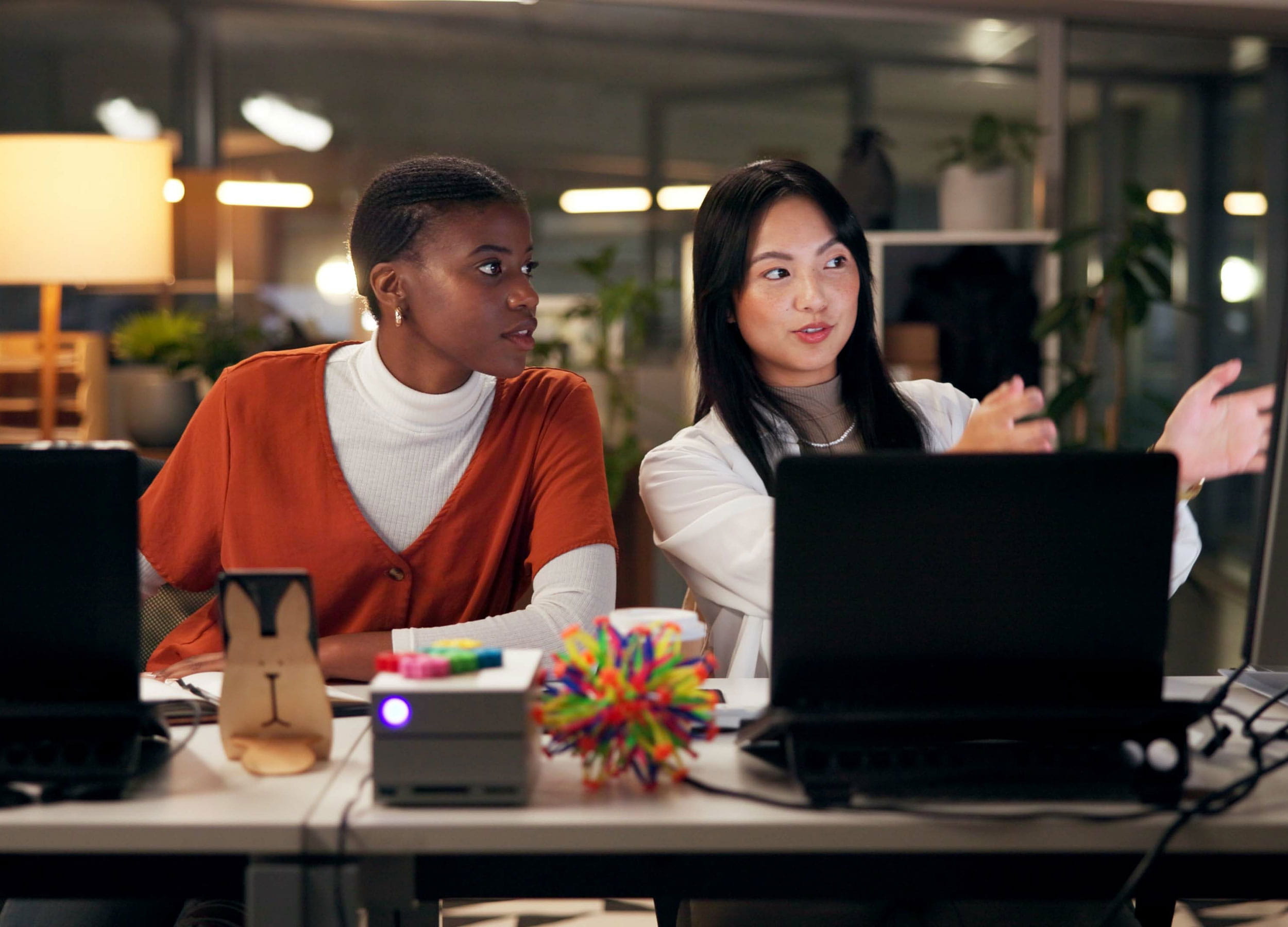 Two people sitting at a desk and looking at a shared computer
