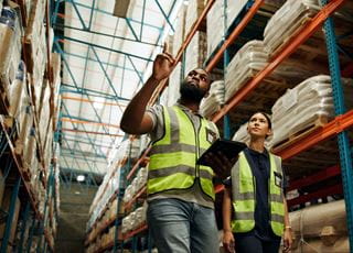 Two people wearing fluorescent vests in a warehouse