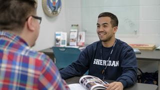 A student talking to another across a desk in Sheridan's Centre for Indigenous Learning and Support