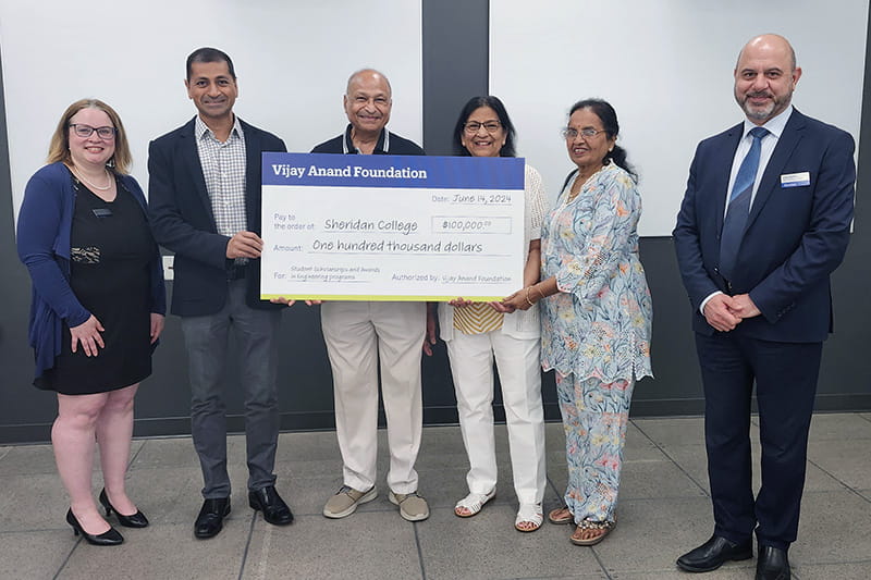 Six people posing with a large cheque